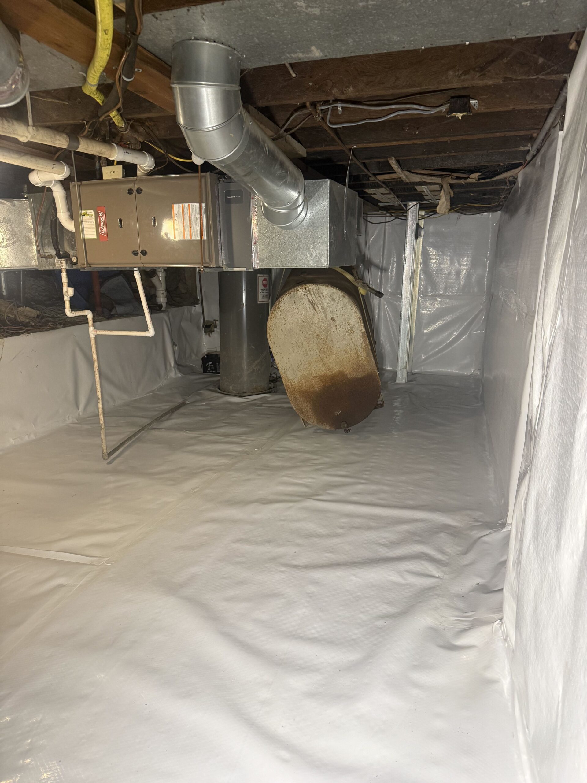 White CleanSpace liner covering the soil floor and foundation walls around basement mechanical equipment.