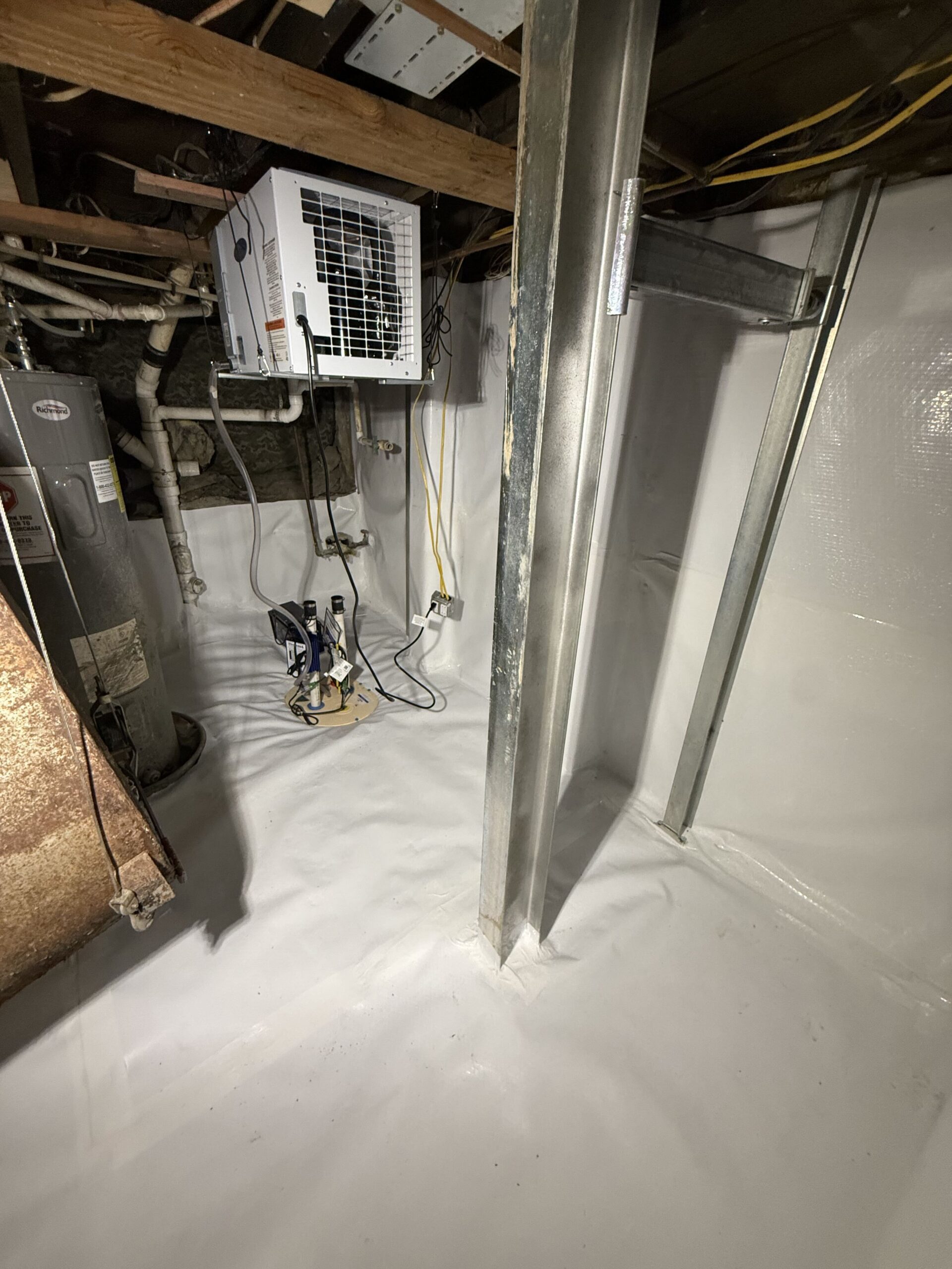 AprilAire basement dehumidifier above a sump basin, with white CleanSpace lining covering the floor and walls.