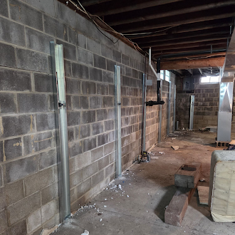 Steel wall anchor components installed along a basement concrete block wall.
